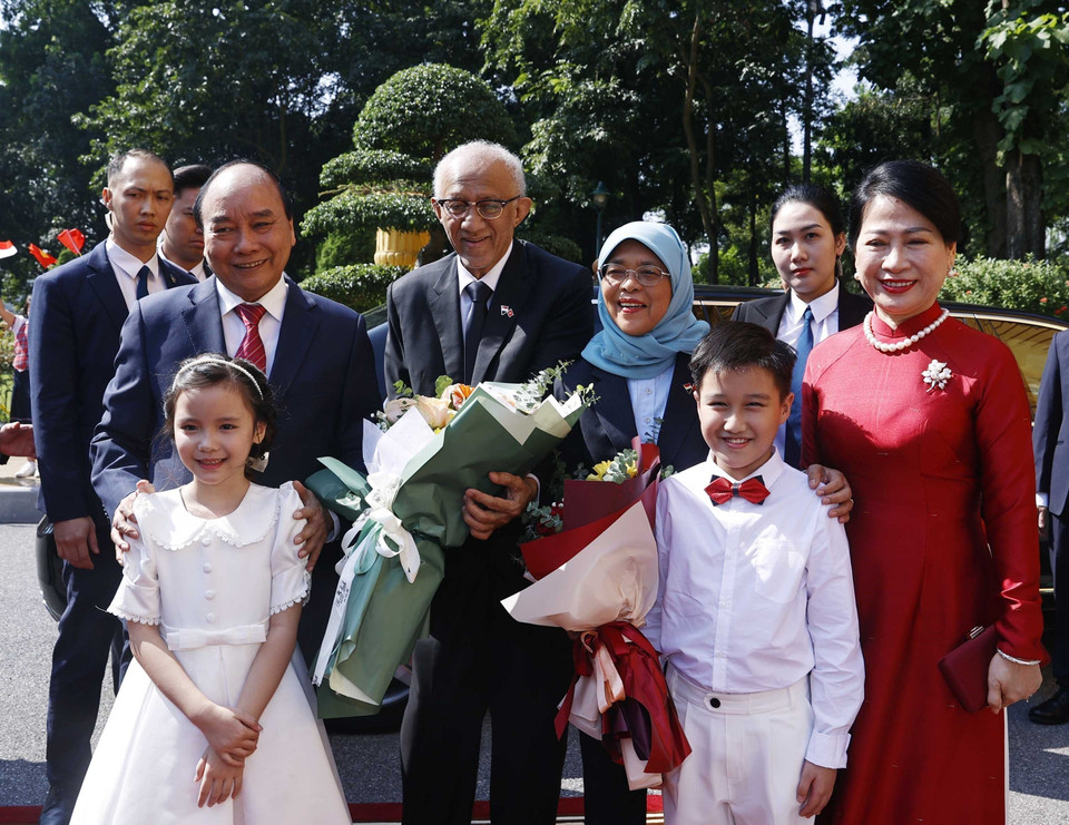 Chủ tịch nước Nguyễn Xuân Phúc và Phu nhân cùng Tổng thống Cộng hòa Singapore Halimah Yacob và Phu quân với thiếu nhi Thủ đô Hà Nội tại lễ đón. (Ảnh: Thống Nhất/TTXVN)