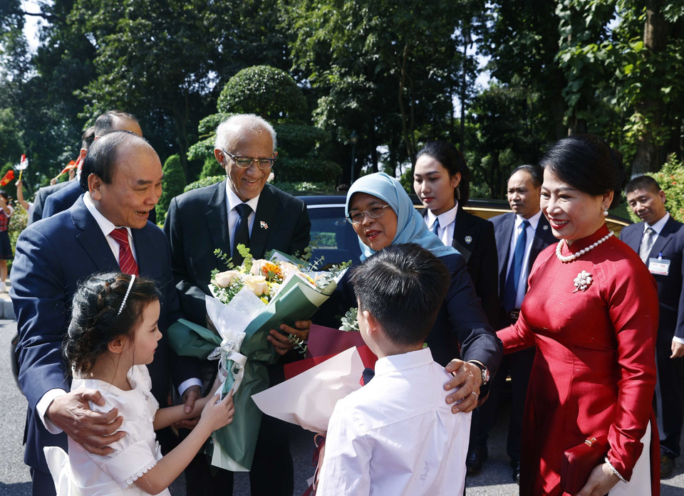 Chủ tịch nước Nguyễn Xuân Phúc và Tổng thống Cộng hòa Singapore Halimah Yacob với thiếu nhi Thủ đô Hà Nội tại lễ đón. (Ảnh: Thống Nhất/TTXVN)