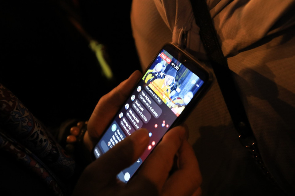 Người dân theo dõi lễ cầu an trực tuyến qua điện thoại di động. (Ảnh: Thành Đạt/TTXVN)