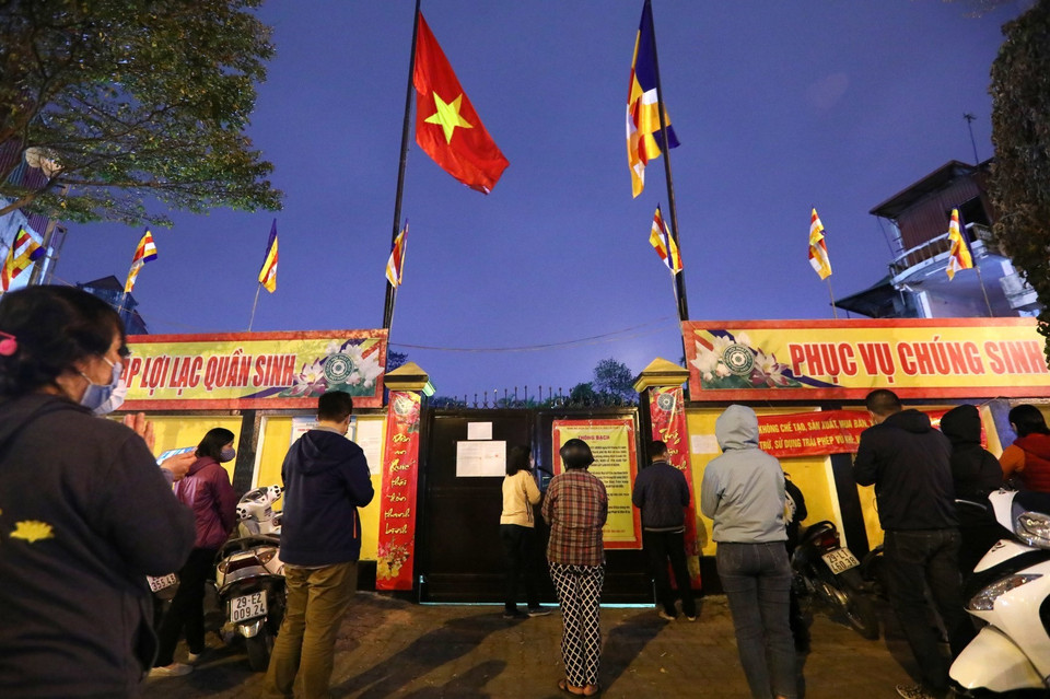 Người dân đứng ngoài chùa Phúc Khánh chắp tay vái vọng cầu bình an. (Ảnh: Thành Đạt/TTXVN)