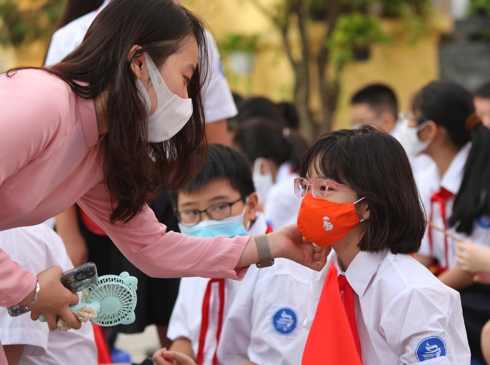 Cô giáo trường THCS Trưng Vương, quận Hoàn Kiếm (Hà Nội) chỉnh trang lại khẩu trang cho học sinh trong lễ khai giảng. (Ảnh: Danh Lam/TTXVN)