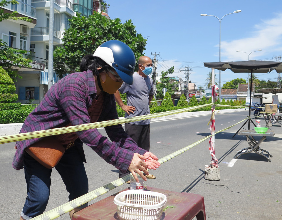 Người mua khử khuẩn sau khi mua hàng tại khu vực chợ dã chiến phường Vạn Thạnh, thành phố Nha Trang, tỉnh Khánh Hòa. (Ảnh: Phan Sáu/TTXVN)