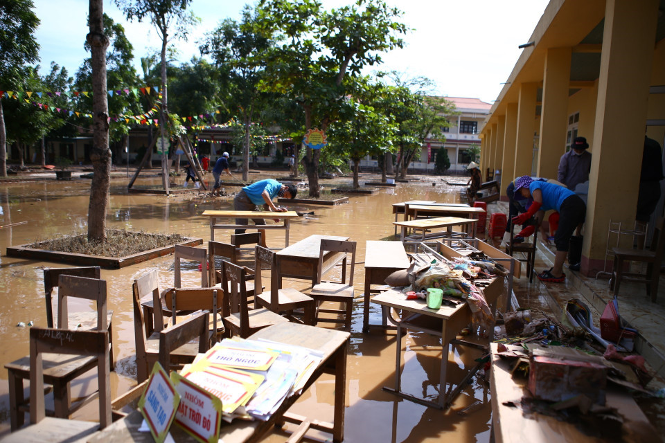 Giáo viên trường tiểu học Cẩm Duệ dọn vệ sinh trường, lớp học ngay khi nước đang rút dần. (Ảnh: Minh Quyết/TTXVN)