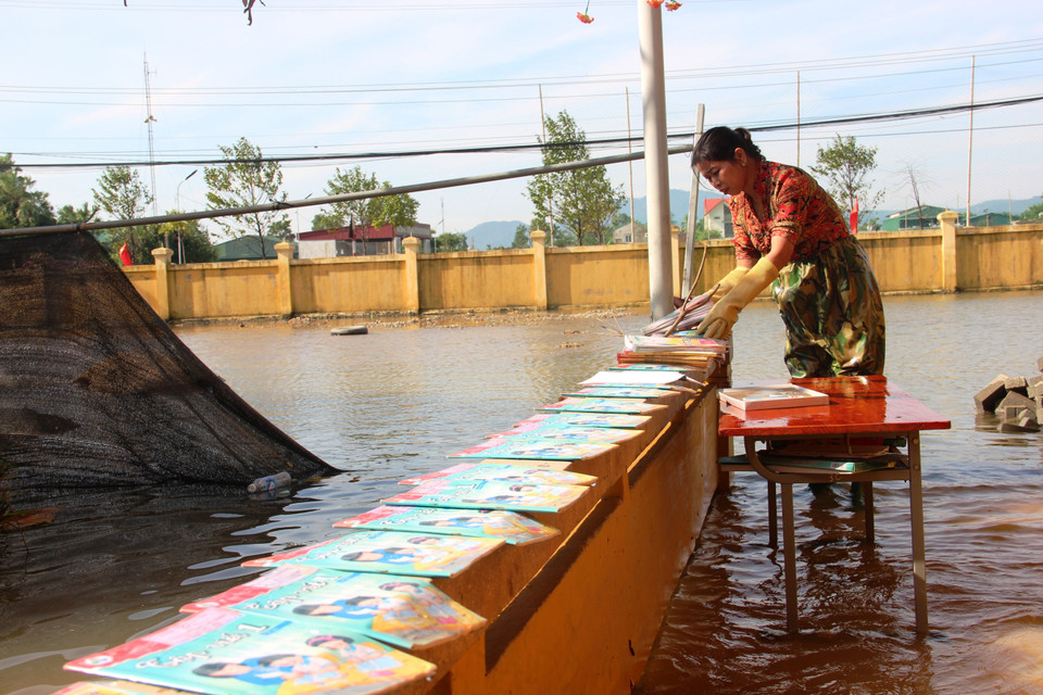 Giáo viên trường Tiểu học Thạch Tân (Xã Tân Lâm Hương, Thạch Hà) phơi sách cho học trò. (Ảnh: Hoàng Ngà/TTXVN)