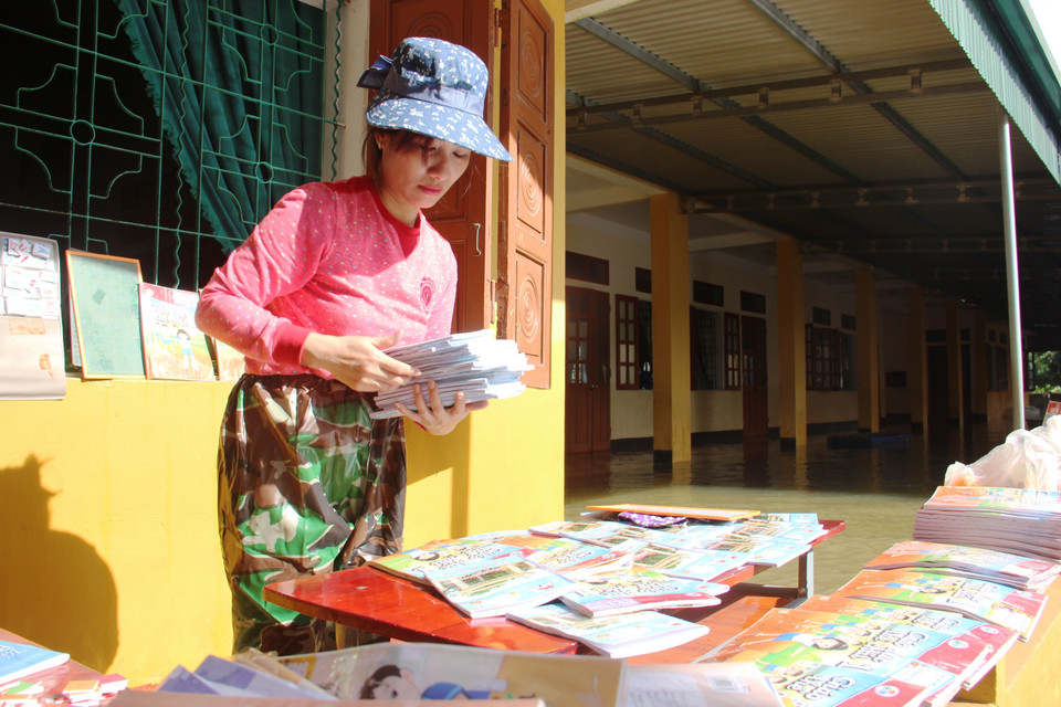 Giáo viên trường Tiểu học Thạch Tân (Xã Tân Lâm Hương, Thạch Hà) phơi sách cho học trò. (Ảnh: Hoàng Ngà/TTXVN)