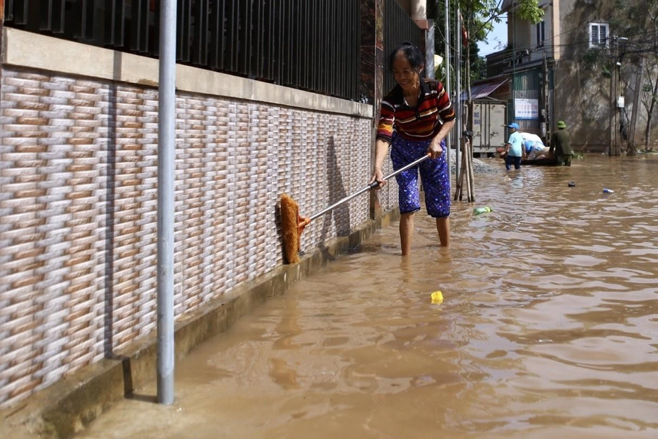 Nước lũ rút dần, người dân thôn Tân Phú, xã Cẩm Duệ, tiến hành dọn vệ sinh nhà cửa. (Ảnh: Minh Quyết/TTXVN)