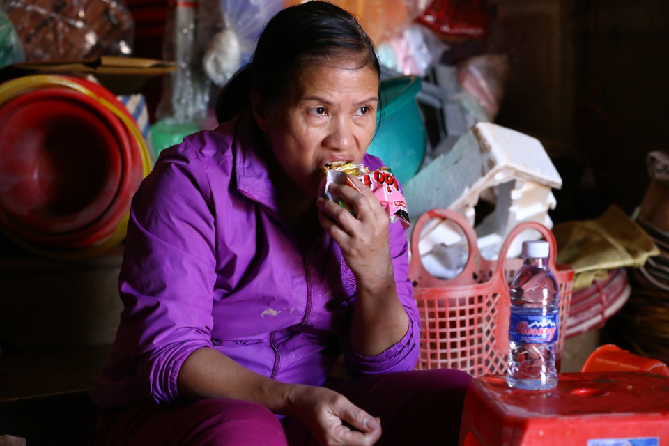 Chị Trần Thị Phương tranh thủ ăn trưa bằng mỳ tôm sống, khi khu vực này chưa có điện, nước trở lại. (Ảnh: Minh Quyết/TTXVN)