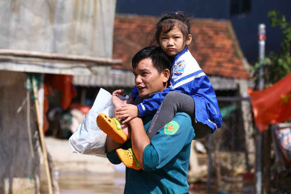 Bố cõng con qua khu vực đội 10, thôn Tân Phú - một trong các điểm ngập sâu nhất của xã Cẩm Duệ. (Ảnh: Minh Quyết/TTXVN)
