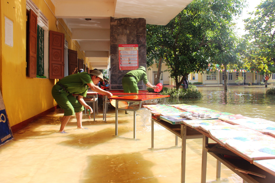 Lực lượng công an huyện Thạch Hà kịp thời có mặt để giúp giáo viên dọn dẹp sau lũ. (Ảnh: Hoàng Ngà/TTXVN)