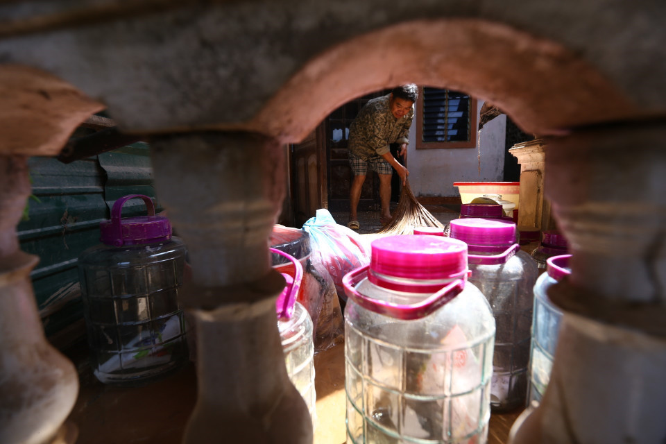 Anh Phạm Ngọc Phúc, thôn Tân Phú, xã Cẩm Duệ dọn dẹp nhà cửa ngay khi nước rút. (Ảnh: Minh Quyết/TTXVN)