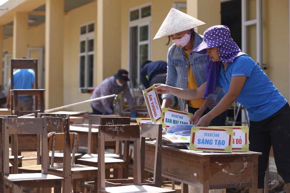 Giáo viên trường tiểu học Cẩm Duệ dọn vệ sinh trường, lớp học ngay khi nước đang rút dần. (Ảnh: Minh Quyết/TTXVN)