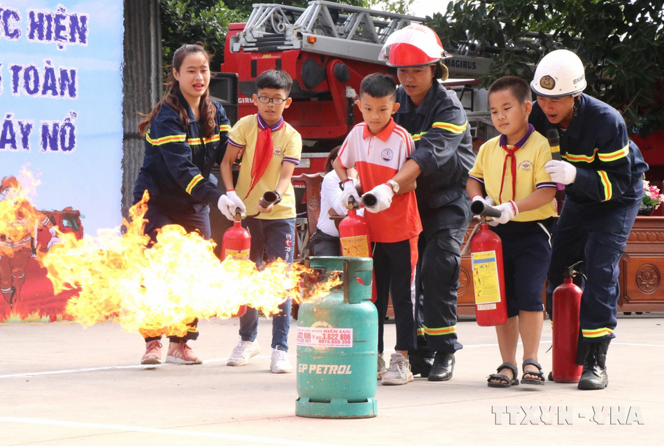 Chiến sỹ Cảnh sát Phòng cháy Chữa cháy, Công an tỉnh Bắc Ninh hướng dẫn học sinh tham gia trải nghiệm "Một ngày làm lính cứu hỏa." (Ảnh: Đinh Văn Nhiều/TTXVN)