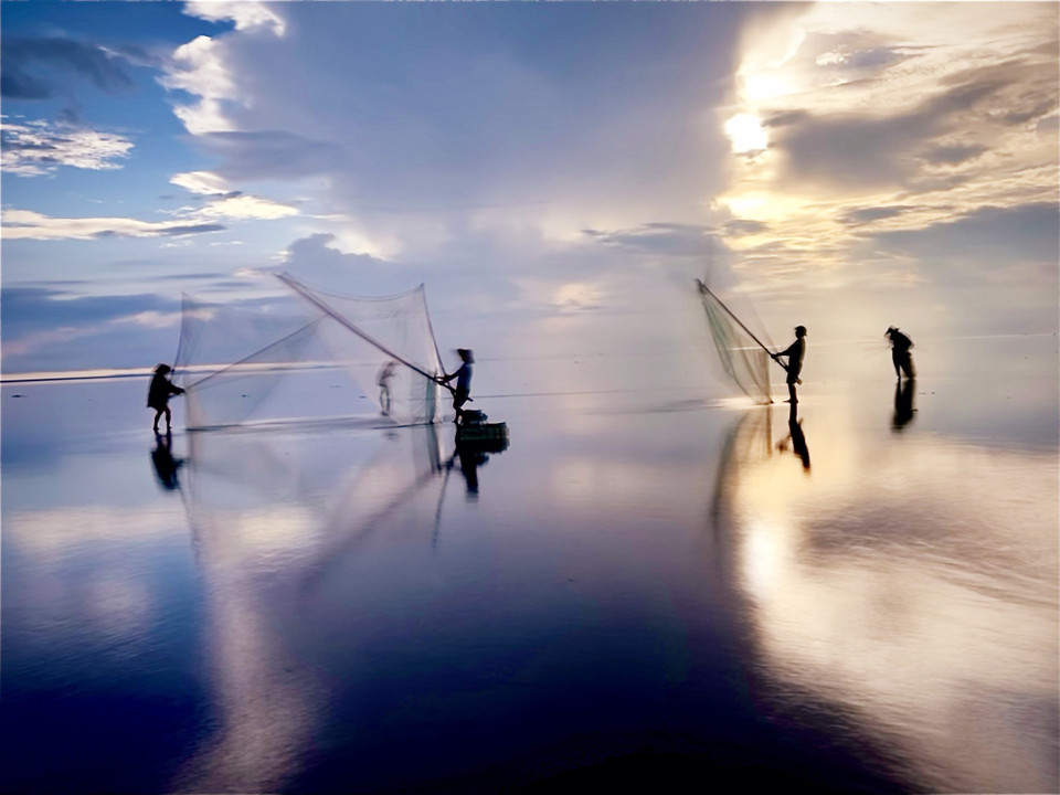 Mặt biển phẳng lặng phản chiếu những tia nắng rực rỡ của buổi sớm mai, tạo nên không gian mênh mang, vô hạn... (Ảnh: Vũ Kim Xuân/Vietnam+)