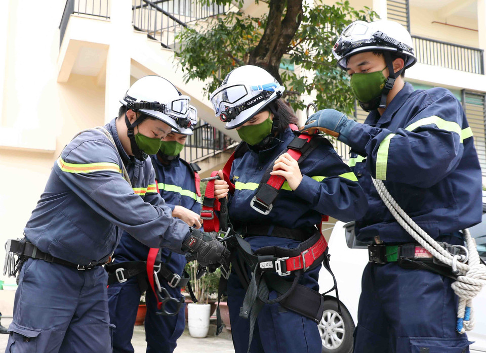 Thiếu tá Nguyễn Thị Ngọc Lan, cán bộ Đội công tác chữa cháy và cứu nạn cứu hộ, Công an thành phố Hà Nội cùng đồng đội chuẩn bị trang thiết bị bảo hộ trước giờ tập luyện. (Ảnh: Phạm Kiên/TTXVN)