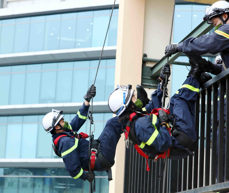 Thiếu tá Nguyễn Thị Ngọc Lan cùng đồng đội nam thực hiện kỹ thuật di chuyển trên cao xuống, đi trên mặt phẳng tường một cách thuần thục. (Ảnh: Phạm Kiên/TTXVN)