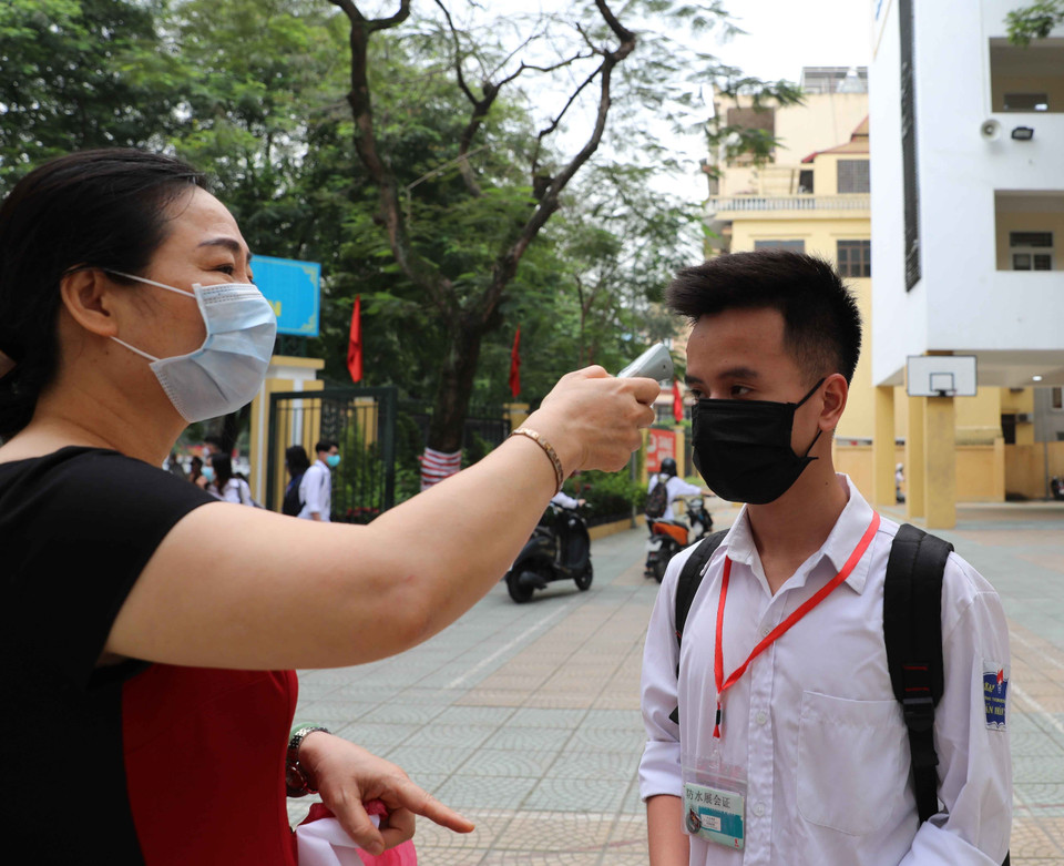 Kiểm tra thân nhiệt cho học sinh ngay khi vào cổng trường. (Ảnh: Thanh Tùng/TTXVN)
