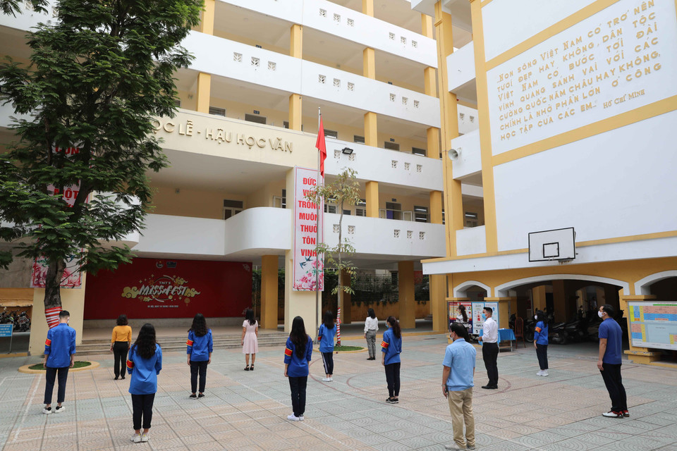 Giáo viên trường THPT Trần Nhân Tông (quận Hai Bà Trưng) chào cờ đầu tuần đảm bảo giãn cách tối thiểu. (Ảnh: Thanh Tùng/TTXVN)