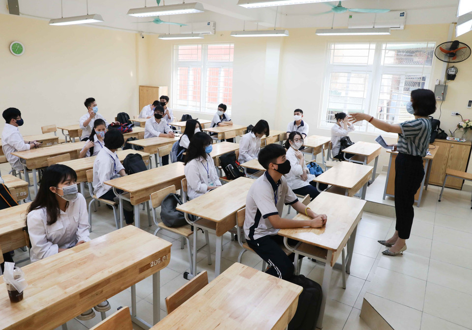 Giáo viên hướng dẫn học sinh ngồi trong lớp theo vị trí đảm bảo giãn cách tối thiểu. (Ảnh: Thanh Tùng/TTXVN)