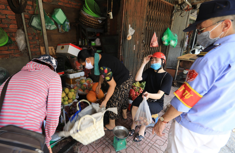 Lực lượng chức năng quận Hai Bà Trưng nhắc nhở, yêu cầu người dân không họp chợ để phòng chống dịch. (Ảnh: Thành Đạt/TTXVN)