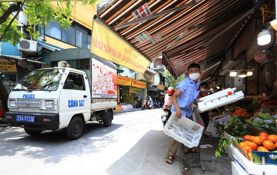 Lực lượng chức năng phường Hàng Bạc giải tỏa các chợ cóc, chợ tạm lấn chiếm vỉa hè, lòng đường nguy cơ lây lan dịch bệnh COVID-19 tại khu vực chợ Hàng Bè. (Ảnh: Thành Đạt/TTXVN)