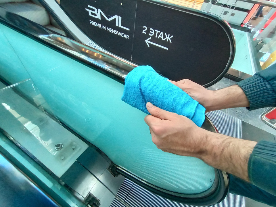 Làm vệ sinh diệt khuẩn trên tay vịn cầu thang cuốn trong trung tâm thương mại. (Ảnh: Trần Hiếu/TTXVN)