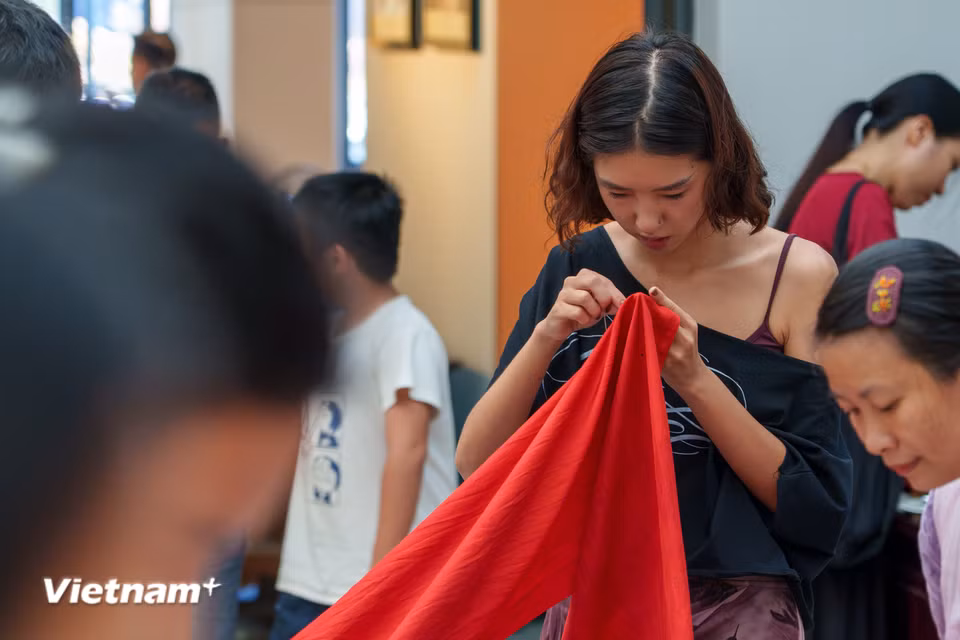 Du khách hào hứng trải nghiệm thao tác khâu và cảm nhận chất liệu tơ lụa tự nhiên tại workshop nghệ thuật cộng đồng “Hương lụa Đồng Dương”. (Ảnh: Thanh Phong/Vietnam+)