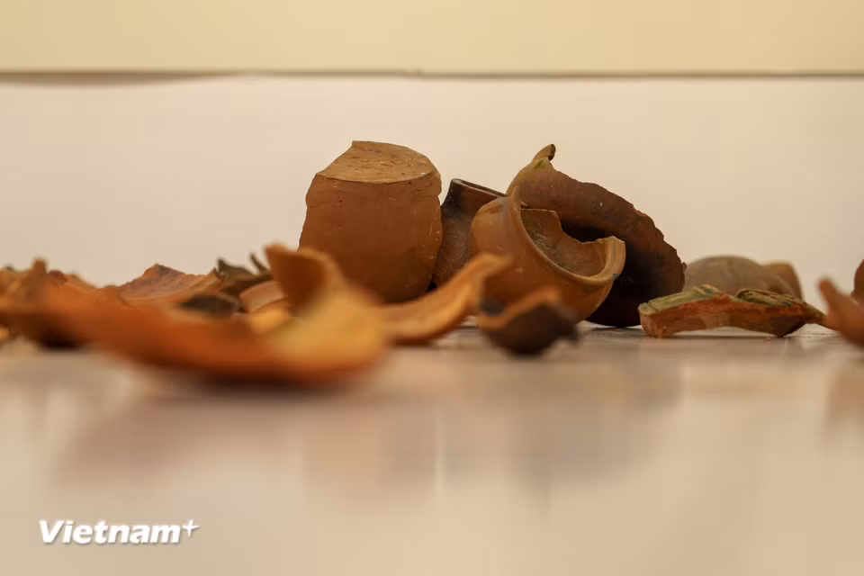 Cận cảnh những mảnh gốm cổ rải trên mặt sàn trong sắp đặt “Những mảnh rời”, hành trình gom nhặt, chắp nối những ký ức văn hóa Chăm qua biến thiên lịch sử. (Ảnh: Thanh Phong/Vietnam+)