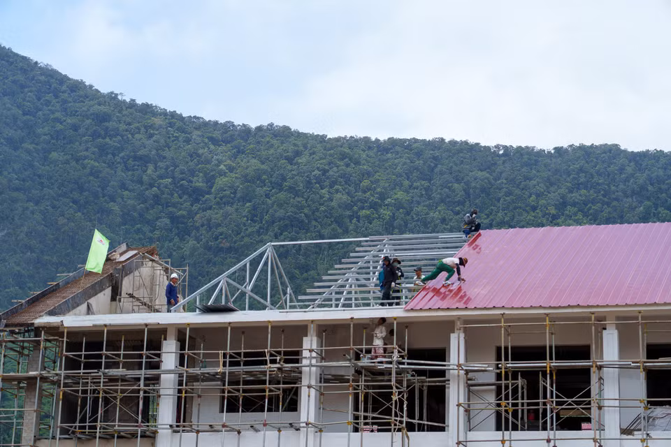 Các công nhân miệt mài thi công lắp đặt hệ thống mái che chống bão cho khối nhà. (Ảnh: Thanh Phong/Vietnam+)