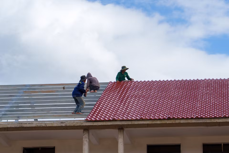 Công nhân đo đạc, kiểm tra kỹ lưỡng độ chính xác của kết cấu thép khung mái trước khi tiến hành lợp. (Ảnh: Thanh Phong/Vietnam+)