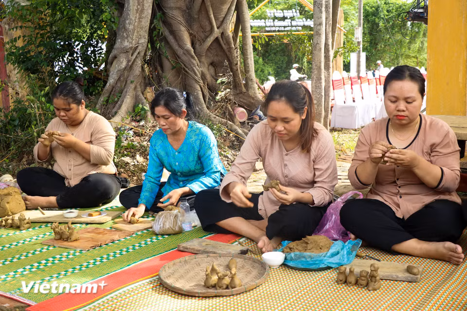 Dưới bóng cây đa cổ thụ, các nữ thợ gốm miệt mài nặn những con tò he đất nhỏ nhắn bằng đôi tay khéo léo. (Ảnh: Thanh Phong/Vietnam+)