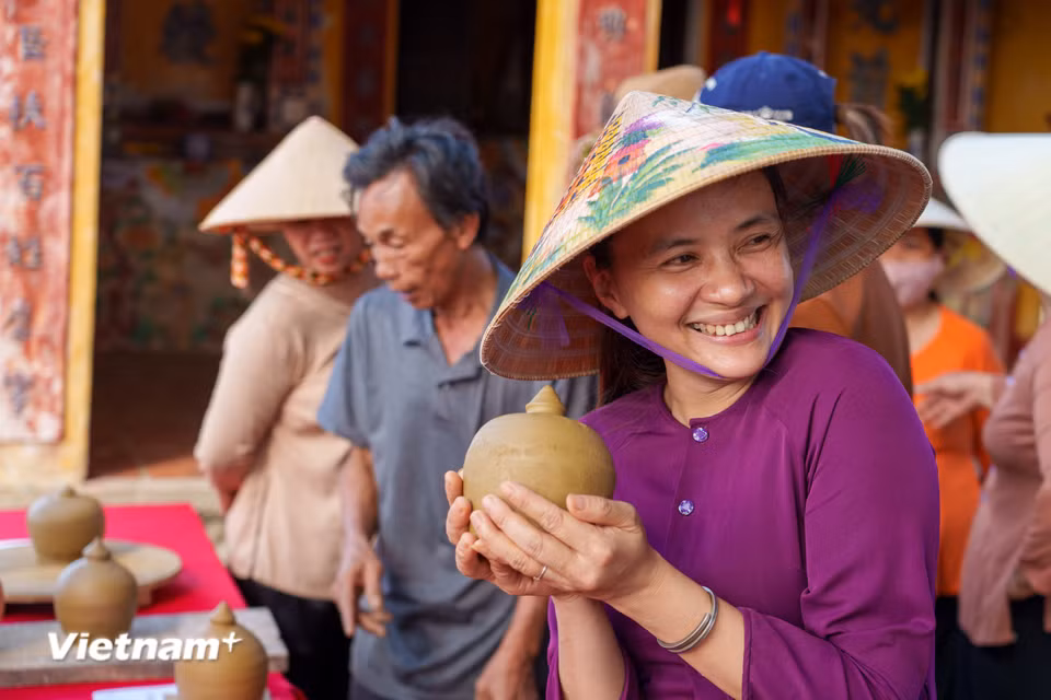Nụ cười rạng rỡ của nữ nghệ nhân làng gốm Thanh Hà khi nâng niu sản phẩm gốm mộc vừa được vuốt nặn thành hình. (Ảnh: Thanh Phong/Vietnam+)