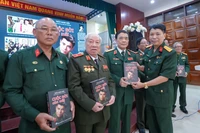 Đại tá Đặng Vương Hưng tặng tác phẩm “Cuộc đời còn mãi” cho các cựu chiến binh. (Ảnh: PV/Vietnam+)