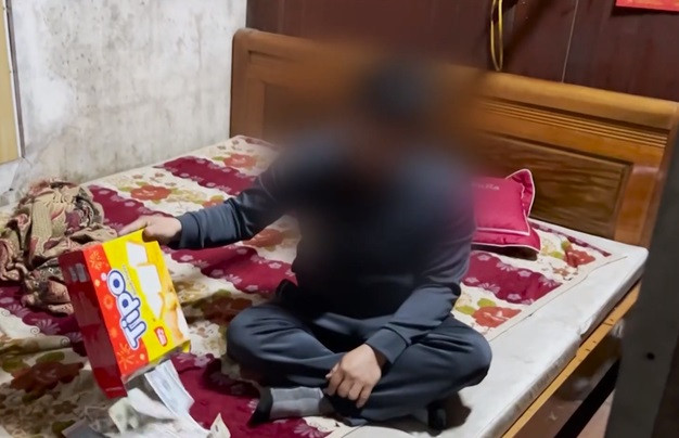 Thành viên Ban quản lý Đền Ông Hoàng Mười ở huyện Hưng Nguyên, tỉnh Nghệ An nhét tiền công đức vào vỏ hộp bánh (Ảnh cắt từ clip)