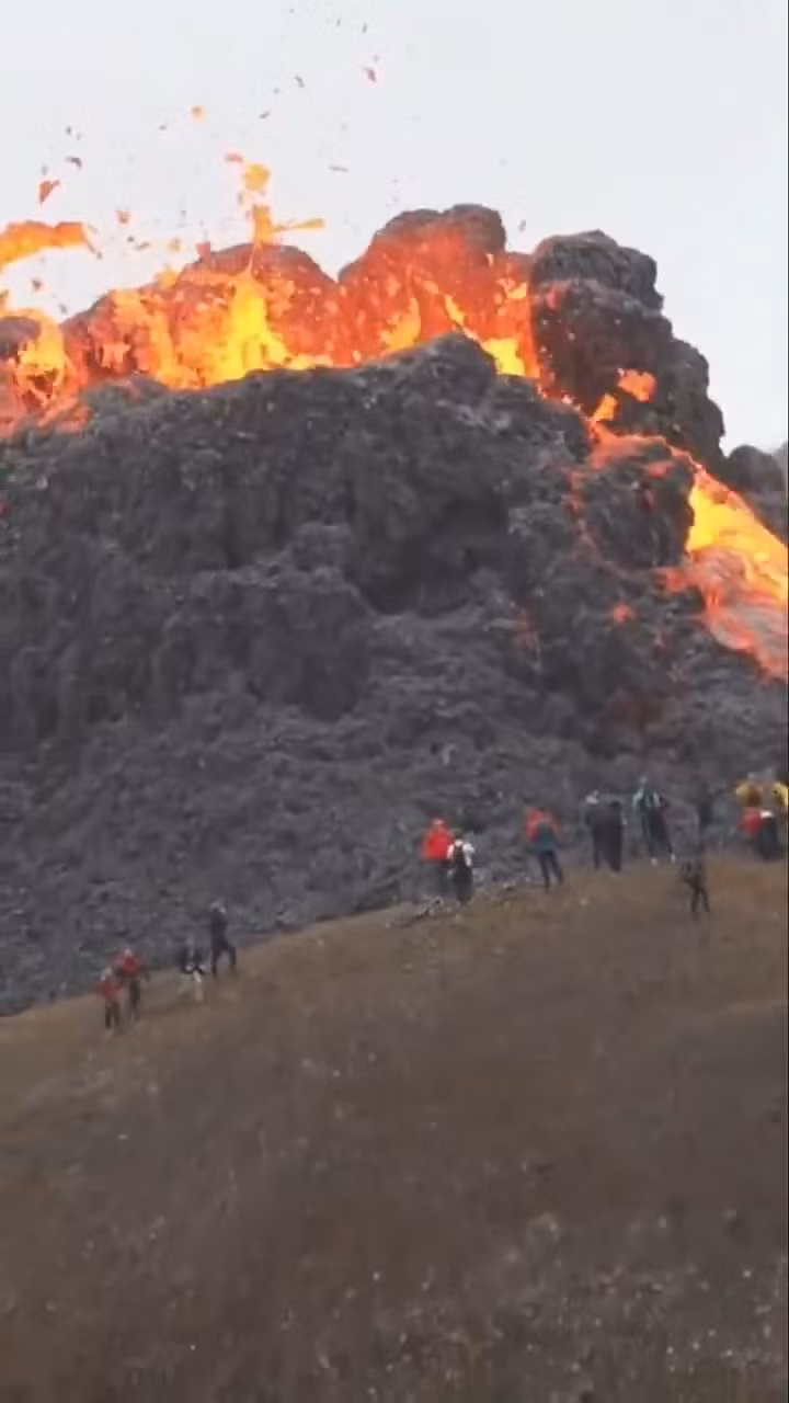 Du khách đứng sát miệng núi lửa để xem nham thạch phun trào ở Iceland