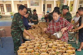 Cục Hậu cần – Kỹ thuật Quân khu 5 tổ chức nấu, cấp phát suất ăn, nước uống, thuốc men hỗ trợ người dân ở vùng ngập sâu. (Ảnh: PV/Vietnam+)