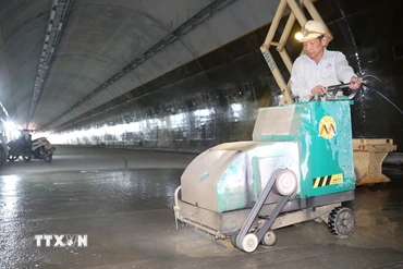 Công nhân thi công hạng mục tạo độ nhám cho mặt đường bên trong hầm. (Ảnh: Hữu Quyết/TTXVN)