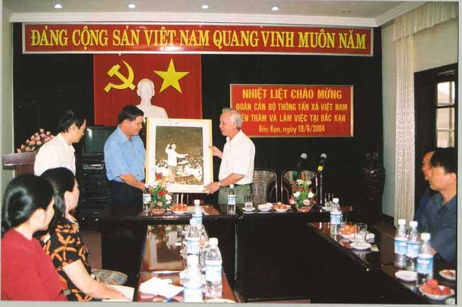 អគ្គនាយករង VNA លោក Nguyen Duy Cuong ប្រគល់រូបថត “ពូហូដឹកនាំចម្រៀងសាមគ្គី” ជូនគណៈកម្មាធិការប្រជាជនខេត្ត Bac Kan ខែសីហា ឆ្នាំ ២០០៤។ Phó Tổng giám đốc TTXVN Nguyễn Duy Cương trao bức ảnh "Bác Hồ bắt nhịp bài ca Kết đoàn" tặng Ủy ban Nhân dân tỉnh Bắc Kạn, tháng 8/2004.