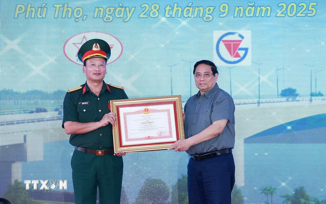 Prime Minister Pham Minh Chinh presented a certificate of merit to comrade Nguyen Tuan Anh, Deputy Commander of Army Corps 12, Ministry of National Defense, for his outstanding achievements in organizing the construction of the new Phong Chau bridge project. (Photo: Duong Giang/VNA) ttxvn-2809-thu-tuong-cau-phong-chau-9.jpg