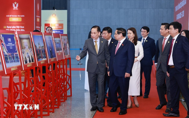 នាយករដ្ឋមន្ត្រី Pham Minh Chinh ទស្សនាការតាំងពិព័រណ៍រូបថតស្តីពីសកម្មភាពការទូត។ (រូបថត៖ Duong Giang/VNA) ttxvn-1011-thu-tuong-dai-hoi-thi-dua-bo-ngoai-giao-2.jpg