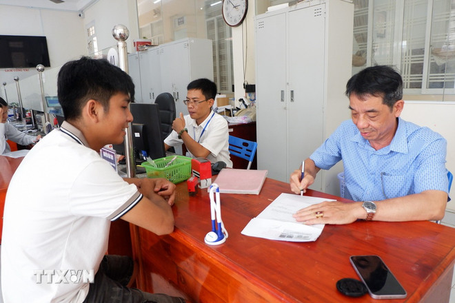 Vu Van Minh, vicevoorzitter van het Volkscomité van de gemeente Tan Hoa, tekent de procedure bij het Openbaar Bestuurscentrum van de gemeente, terwijl er veel documenten zijn. (Foto: Duc Hanh/VNA) ttxvn-1410-tan-hoa-tay-ninh-chinh-quyen-2-cap-3.jpg
