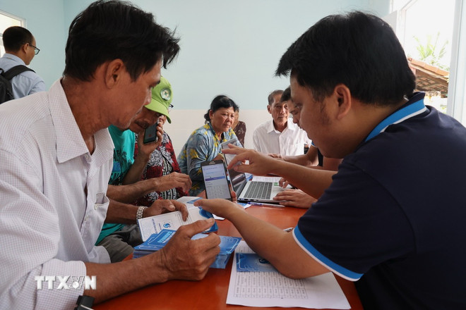 El personal de Sawaco instruye a los usuarios sobre cómo utilizar la aplicación de pago de facturas de agua en línea desde sus teléfonos. (Foto: Anh Tuan/VNA) ttxvn-2910-sawaco-3.jpg