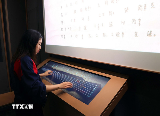 With the support of technology, visitors can play a complete piece of music with an electronic guqin. (Photo: Van Diep/VNA) ttxvn-2205-vu-han-3.jpg