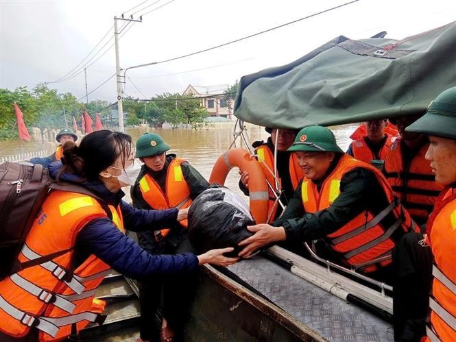 Đại tá Nguyễn Văn Hòa, Phó Tham mưu trưởng Quân khu 5, trực tiếp trao nhu yếu phẩm thiết yếu cho người dân vùng ngập lũ. (Ảnh: Đoàn Hữu Trung/TTXVN)
