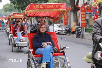 Du khách nước ngoài thích thú với khí hậu mát lạnh của Thủ đô Hà Nội. (Ảnh: Phan Phương/TTXVN)