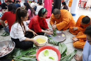 Các chú tiểu tại Chùa Phổ Phước rất quan tâm tìm hiểu văn hóa phong tục tập quán đón Tết của Việt Nam qua việc gói bánh chưng, bánh tét. (Ảnh: Đỗ Sinh/TTXVN)