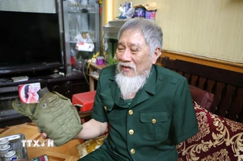 Ông Nguyễn Thế Tám nâng niu chiến tích tịch thu được của quân địch trong thời gian tham gia giải phóng Sài Gòn. (Ảnh: Công Luật/TTXVN)