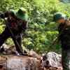 Đội quy tập hài cốt liệt sỹ dùng dụng cụ thô sơ cạy từng tảng đá, tìm kiếm hài cốt liệt sỹ tại Điểm cao 685. (Ảnh minh họa: TTXVN phát)