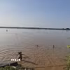 Chỉ vài chục mét sau biển cảnh báo nguy hiểm, nhiều người vẫn vô tư tắm ở bãi tắm tự phát bên bờ sông Hồng, đoạn qua phường Phú Thượng. (Ảnh: Nguyễn Thắng/TTXVN)