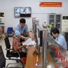 Cán bộ Trung tâm phục vụ hành chính công xã Yên Mỹ hướng dẫn hỗ trợ người già thực hiện thủ tục hành chính. (Ảnh: Mạnh Khánh/TTXVN)