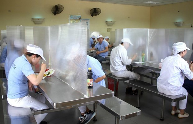 Nhà ăn của công nhân có vách ngăn, đảm bảo giãn cách để phòng, chống COVID-19. (Nguồn: TTXVN) Tăng tốc phục hồi sản xuất: Xem xét sửa đổi quy định về làm thêm giờ ảnh 1